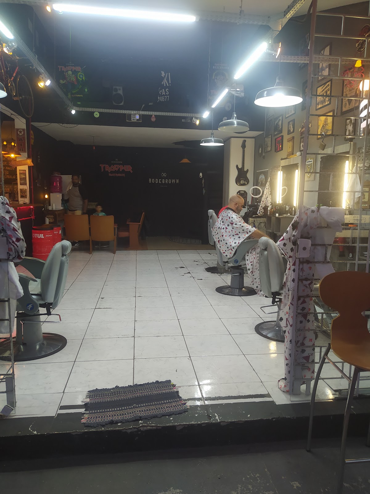 Interior da barbearia com decoração de rock, cadeiras e piso ladrilhado