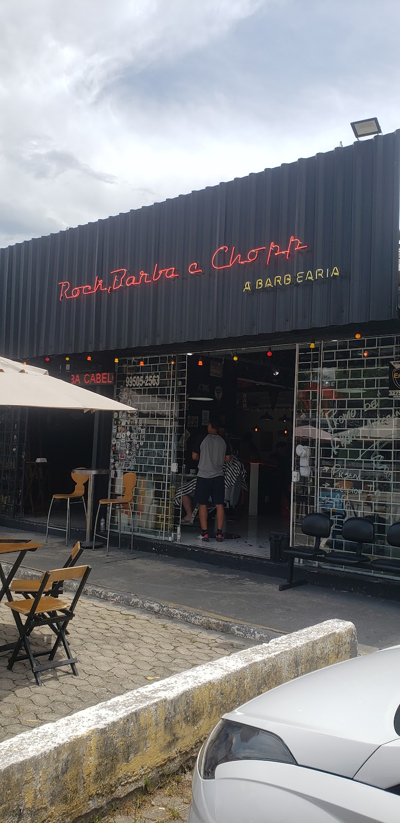Fachada da barbearia à noite com letreiro de neon vermelho 